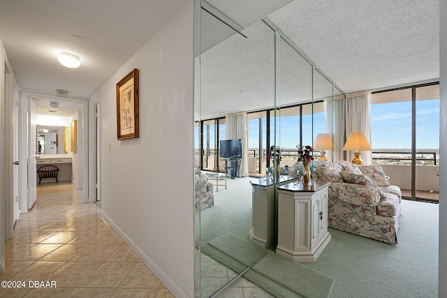 hallway featuring a wall of windows, a textured ceiling, and light tile patterned floors