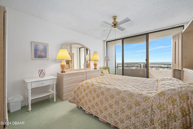 bedroom featuring a textured ceiling, expansive windows, carpet floors, and ceiling fan