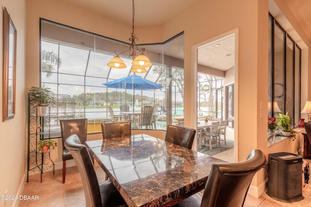tiled dining room featuring a water view, a textured ceiling, and a chandelier