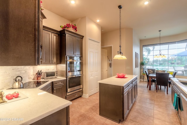 kitchen with black electric stovetop, tasteful backsplash, stainless steel double oven, a kitchen island, and hanging light fixtures