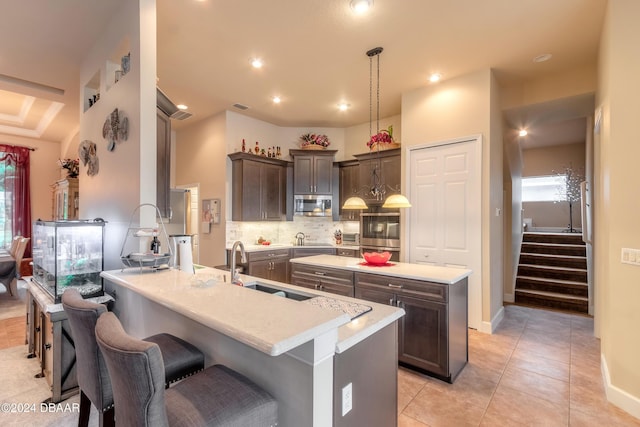 kitchen featuring backsplash, sink, hanging light fixtures, a kitchen island, and light tile patterned flooring