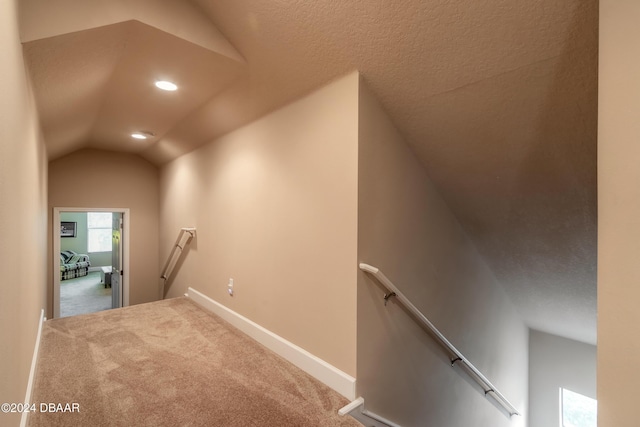 stairs featuring carpet flooring, a textured ceiling, and lofted ceiling