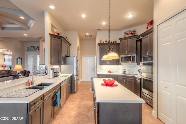 kitchen with pendant lighting, sink, decorative backsplash, light tile patterned floors, and appliances with stainless steel finishes