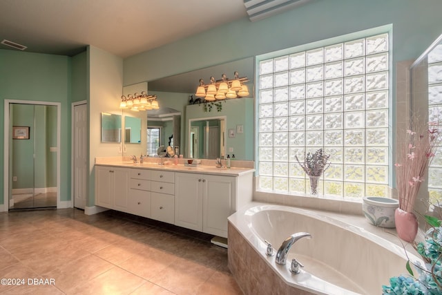 bathroom with tile patterned flooring, vanity, and tiled tub