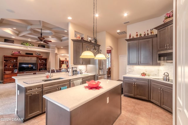kitchen featuring appliances with stainless steel finishes, coffered ceiling, sink, pendant lighting, and a kitchen island