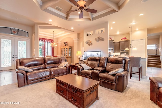 carpeted living room featuring ornate columns, ornamental molding, coffered ceiling, ceiling fan with notable chandelier, and beam ceiling
