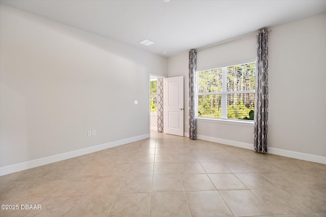 empty room with light tile patterned flooring and baseboards