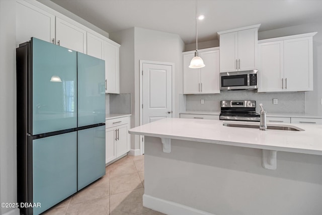 kitchen featuring tasteful backsplash, light countertops, stainless steel appliances, white cabinetry, and a sink