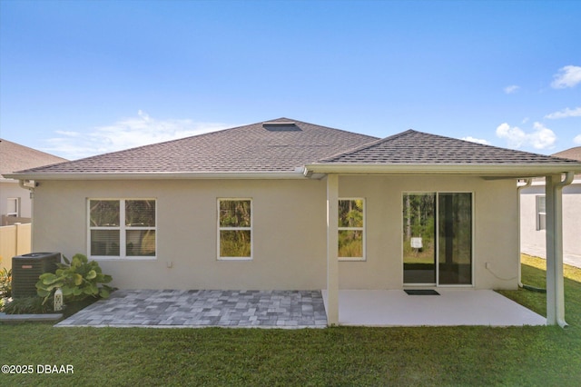 rear view of house featuring central air condition unit, stucco siding, a patio, and a yard