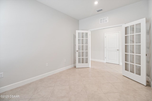 empty room with light tile patterned floors, french doors, baseboards, and visible vents