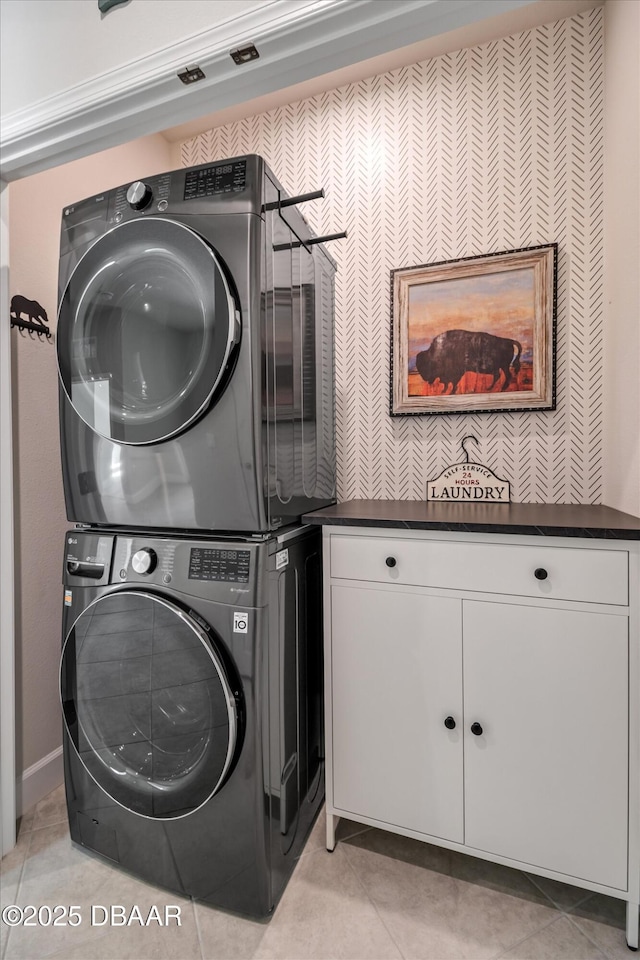 laundry area featuring light tile patterned flooring, cabinet space, and stacked washer and dryer