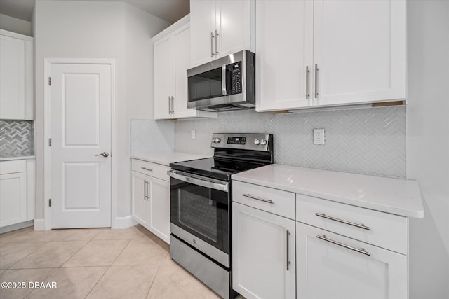 kitchen with tasteful backsplash, light countertops, light tile patterned flooring, white cabinets, and stainless steel appliances