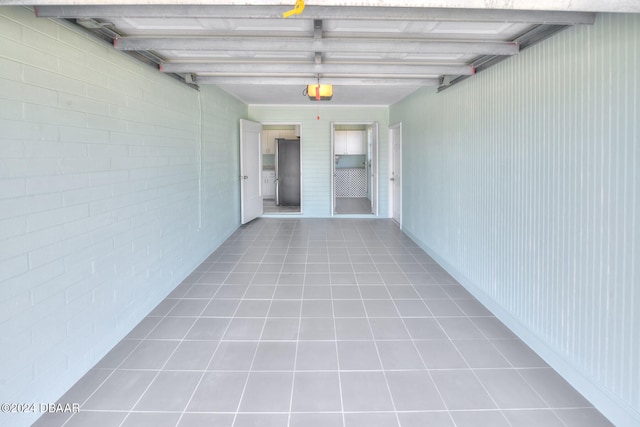 hall featuring brick wall, beamed ceiling, and light tile patterned floors