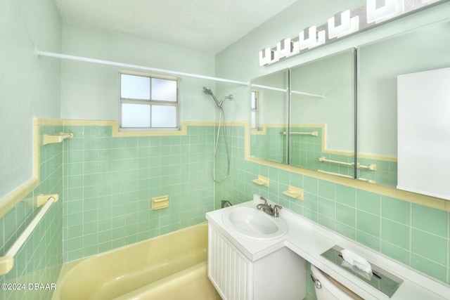 bathroom featuring tile walls, vanity, a textured ceiling, decorative backsplash, and tiled shower / bath