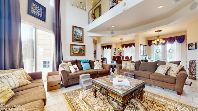 living room with a healthy amount of sunlight, light tile patterned floors, a high ceiling, and an inviting chandelier