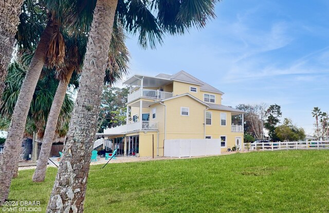 rear view of property with a balcony and a yard