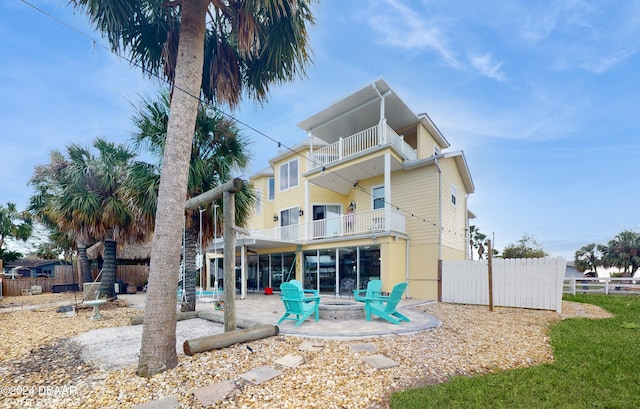 rear view of property with a fire pit, a patio area, and a balcony