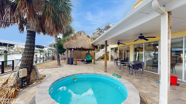 view of pool with a gazebo, a water view, ceiling fan, and a patio