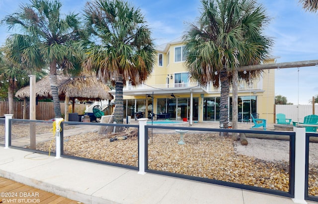 view of front of property featuring a fenced in pool, a balcony, ceiling fan, and a patio area