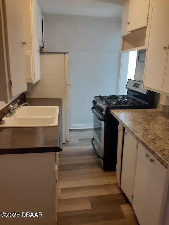 312 Frances Ter, Daytona Beach, FL 32118 - kitchen with gas range, white cabinetry, and light wood finished floors