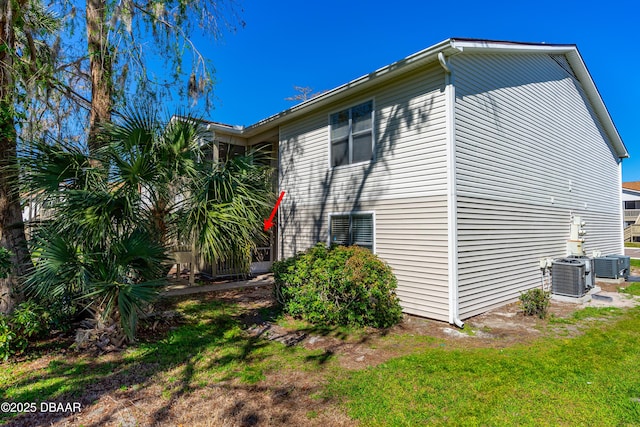 view of side of home featuring a lawn and central AC