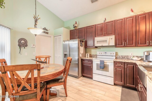 198 Heather Lane Dr, Deltona, FL 32738 - kitchen with white appliances, high vaulted ceiling, light stone counters, and light wood finished floors