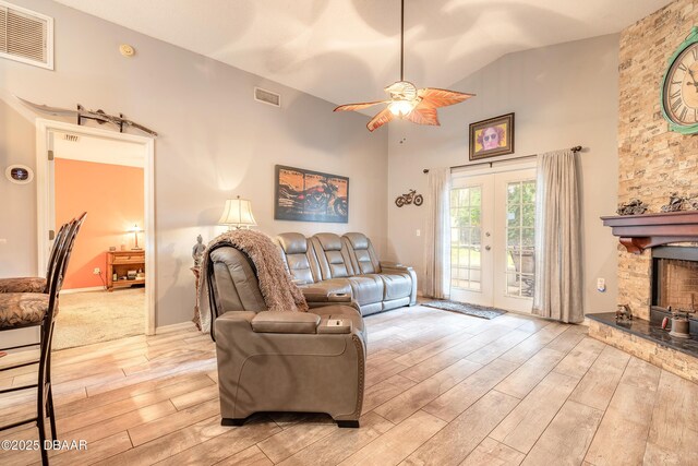 198 Heather Lane Dr, Deltona, FL 32738 - living room featuring light wood finished floors, ceiling fan, high vaulted ceiling, french doors, and a stone fireplace