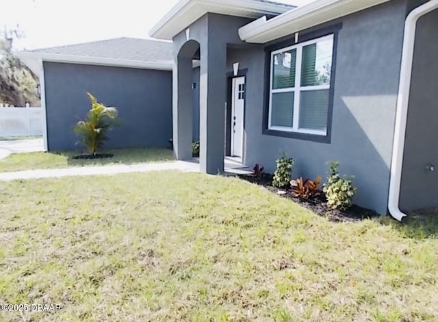 doorway to property with a lawn and stucco siding