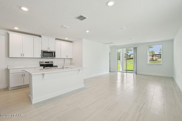 288 Links Terrace Blvd, Daytona Beach, FL 32124 - kitchen featuring stainless steel microwave, electric range oven, light countertops, open floor plan, and a center island with sink
