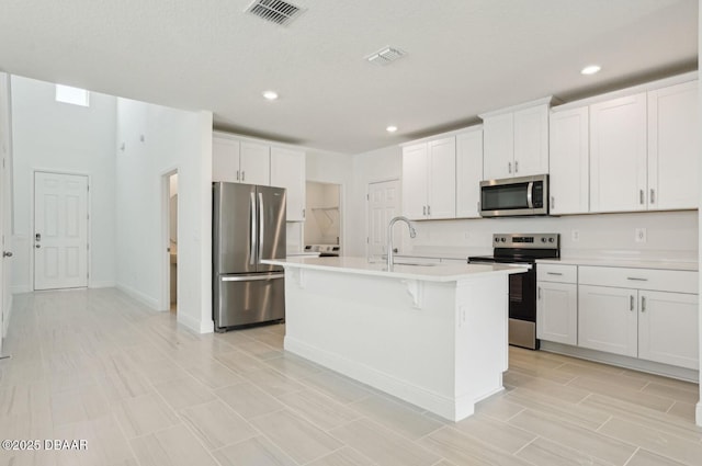 288 Links Terrace Blvd, Daytona Beach, FL 32124 - kitchen featuring appliances with stainless steel finishes, light countertops, recessed lighting, an island with sink, and white cabinetry