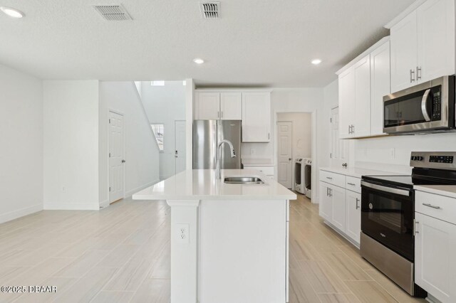 288 Links Terrace Blvd, Daytona Beach, FL 32124 - kitchen with appliances with stainless steel finishes, separate washer and dryer, light countertops, an island with sink, and recessed lighting