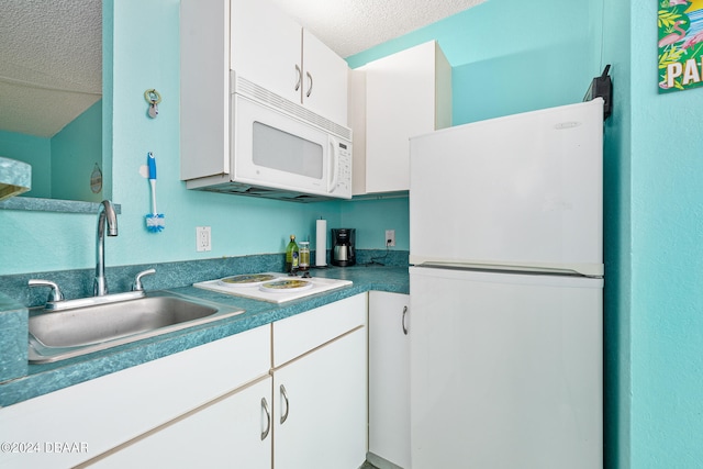 kitchen with white cabinets, a textured ceiling, white appliances, and sink