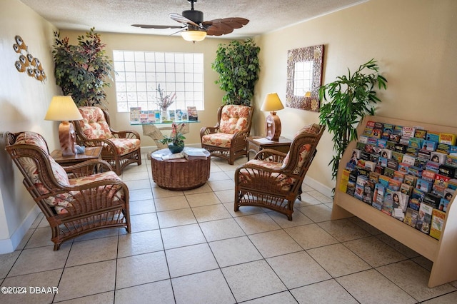 living area with a textured ceiling, ceiling fan, and light tile patterned floors