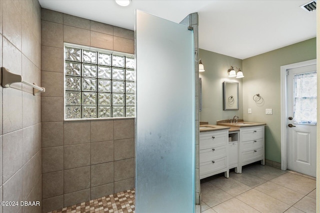 bathroom featuring tile patterned flooring, vanity, tiled shower, and plenty of natural light