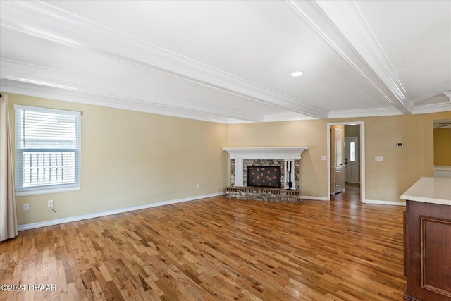 unfurnished living room with beam ceiling, crown molding, hardwood / wood-style floors, and a brick fireplace