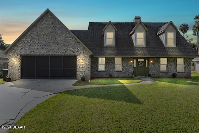 cape cod house with a lawn and a garage