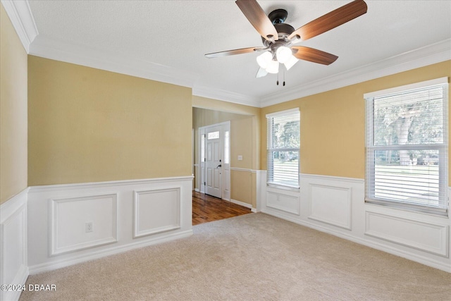 empty room with ceiling fan, light colored carpet, ornamental molding, and a textured ceiling