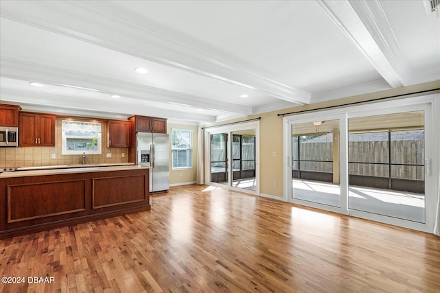 kitchen featuring decorative backsplash, light wood-type flooring, ornamental molding, appliances with stainless steel finishes, and beamed ceiling