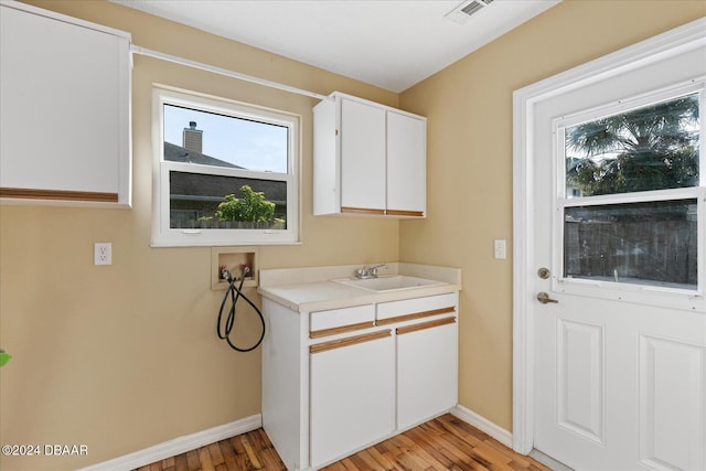 washroom with hookup for a washing machine, light hardwood / wood-style flooring, cabinets, and sink