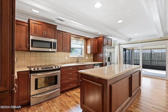 kitchen with sink, light wood-type flooring, ornamental molding, appliances with stainless steel finishes, and beam ceiling