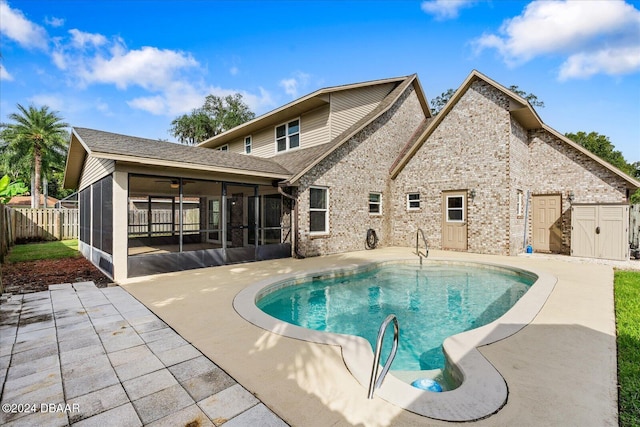 view of pool featuring a sunroom, a patio, and a shed