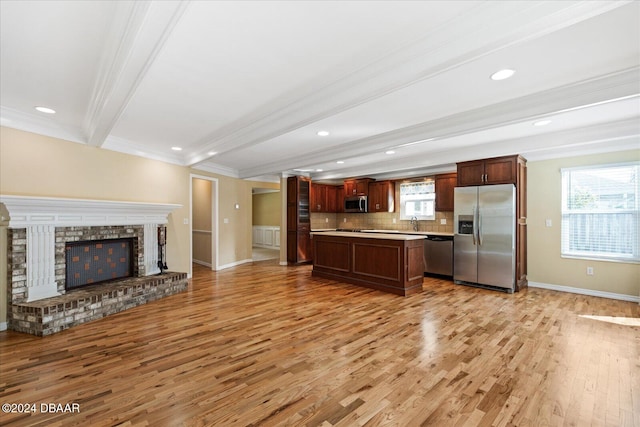 kitchen with a brick fireplace, light wood-type flooring, ornamental molding, beamed ceiling, and stainless steel appliances