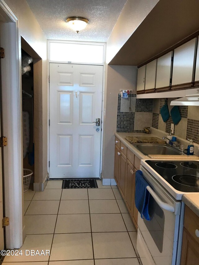 kitchen with a textured ceiling, light tile patterned floors, sink, and white range with electric cooktop