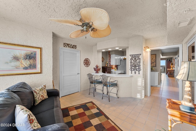 living room featuring light tile patterned flooring, ceiling fan, and a textured ceiling