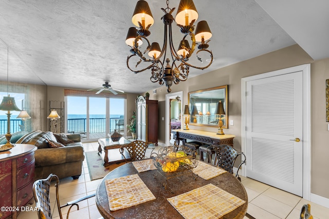 tiled dining area featuring ceiling fan with notable chandelier, a textured ceiling, and a water view