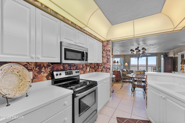 kitchen with white cabinetry, stainless steel appliances, a chandelier, and light tile patterned floors