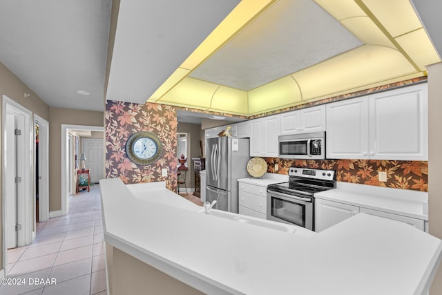 kitchen featuring light tile patterned flooring, stainless steel appliances, sink, white cabinets, and kitchen peninsula