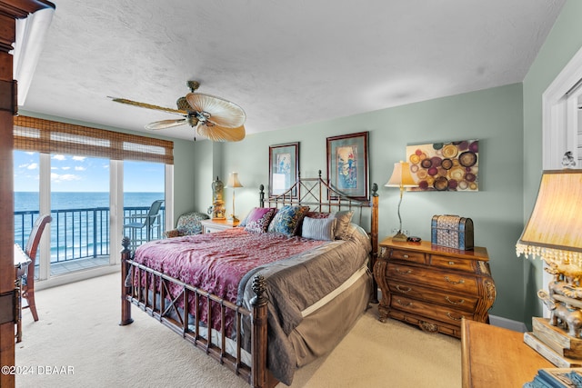 bedroom with access to exterior, light colored carpet, a water view, and ceiling fan