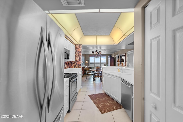 kitchen featuring stainless steel appliances, kitchen peninsula, light tile patterned flooring, ceiling fan, and white cabinetry