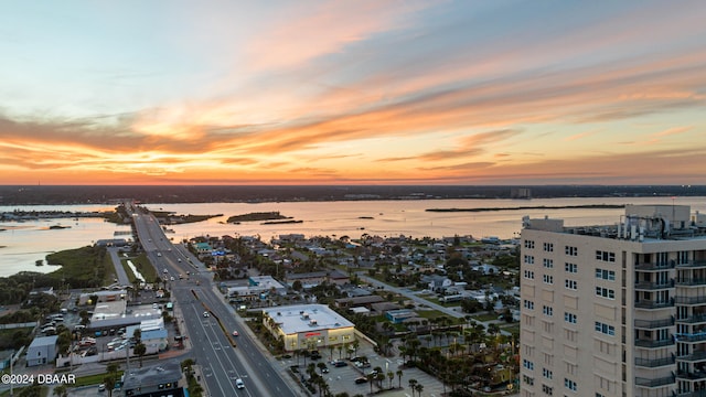 aerial view at dusk featuring a water view